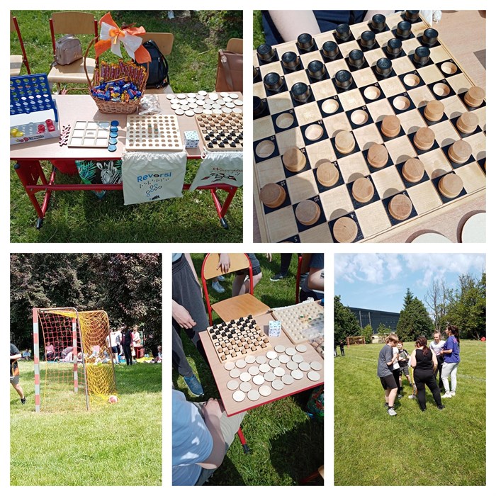 Kolaż 5 zdjęć. Na pierwszym zdjęciu widać stół z krzesłami ustawiony na trawie, na którym znajdują się gry planszowe oraz koszyk ze słodyczami. Kolejne zdjęcie przedstawia drewniane warcaby firmy Altix. Trzecie zdjęcie to piłka w bramce oraz ludzie w tle. Czwarte zdjęcia to ponownie stół z drewnianymi grami oraz kostką Rubika przystosowaną dla osób niewidomych. Na ostatnim zdjęciu widzimy grupę uczniów na murawie boiska.