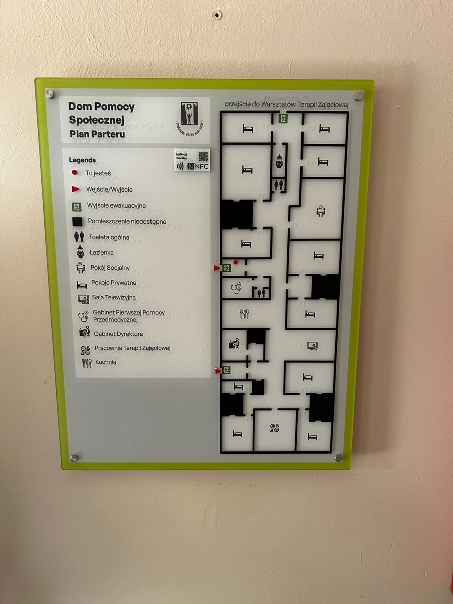 Plan informacyjny piętra „Warsztaty Terapii Zajęciowej” z wypukłymi elementami, technologią NFC i YourWay Beacon oraz oznaczeniami istotnych pomieszczeń.